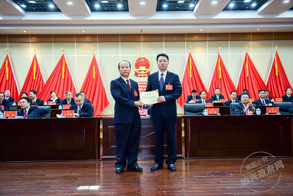 李勇當(dāng)選為始興縣人民政府副縣長(zhǎng)，，圖為賴根為李勇右）頒發(fā)當(dāng)選證書(shū)